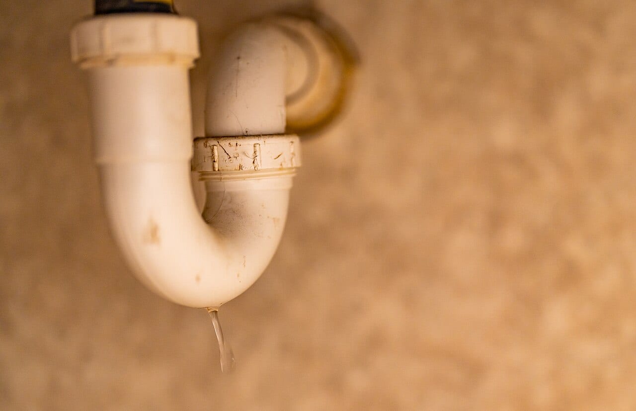 Water dripping from a white under-sink P-trap
