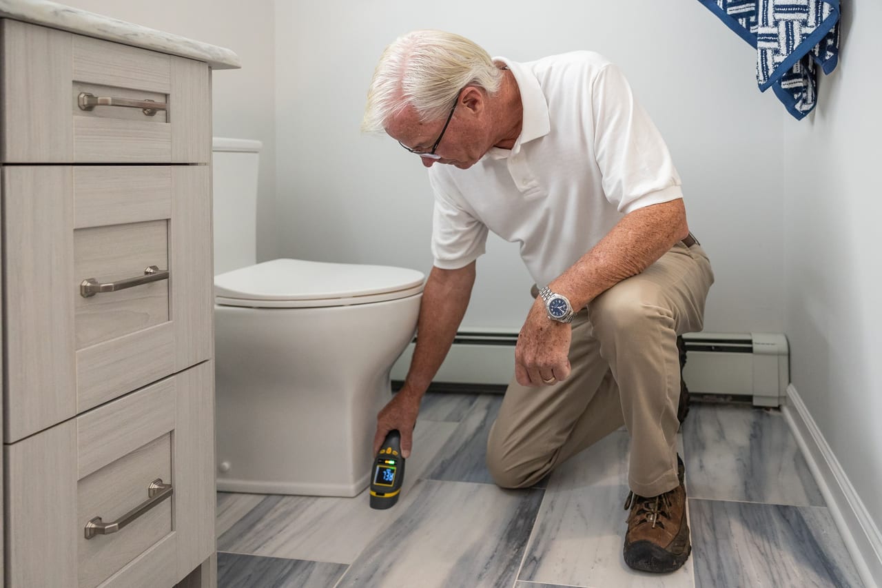 Person inspecting a bathroom floor with a handheld device